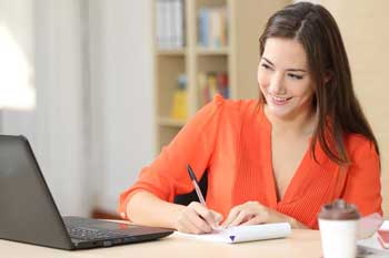 woman-writing-a-desk-with-smile